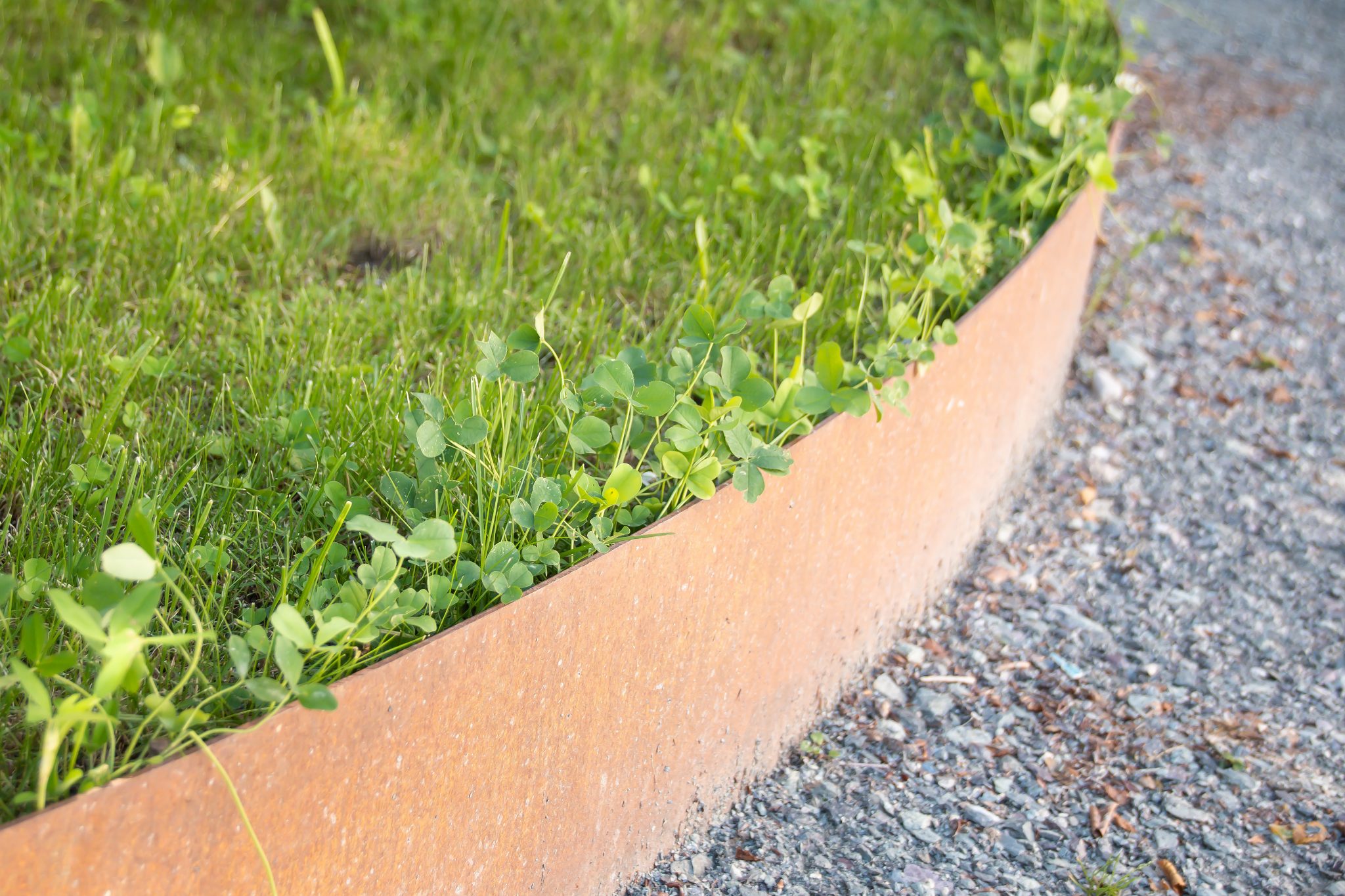 Steel garden edging separating a lawn from a gravel path