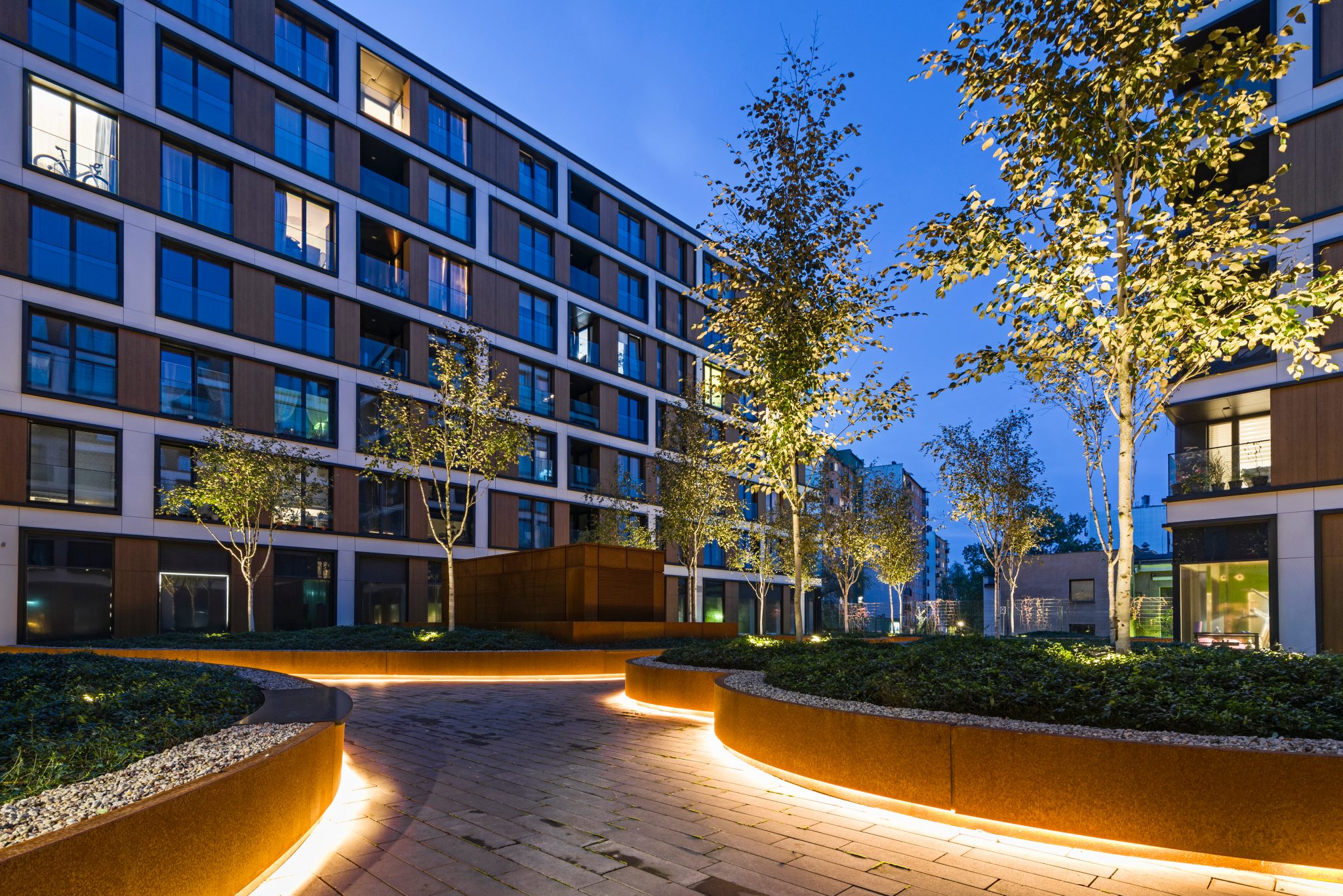 Curved Corten steel retaining wall holding a raised planted bed above a path